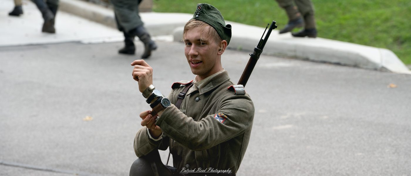 A German soldier displaying watches he collected from fallen soldiers, a grim testament to the harsh realities of war. The soldier's expression is a mix of pride and indifference, reflecting the brutal nature of conflict and the personal toll it takes.